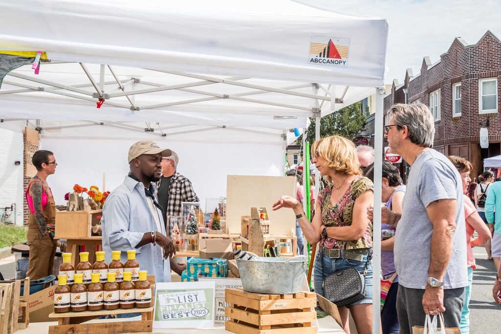 Attendees at an event talk to a vendor at his stall.